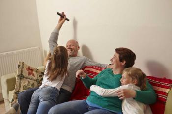Mum, dad and adopted daughters playing on sofa