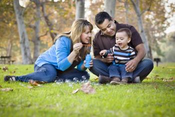 Ethnically diverse family blowing bubbles in the park